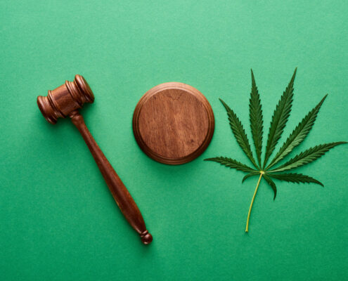 top view of green marijuana leaf with wooden gavel on green background